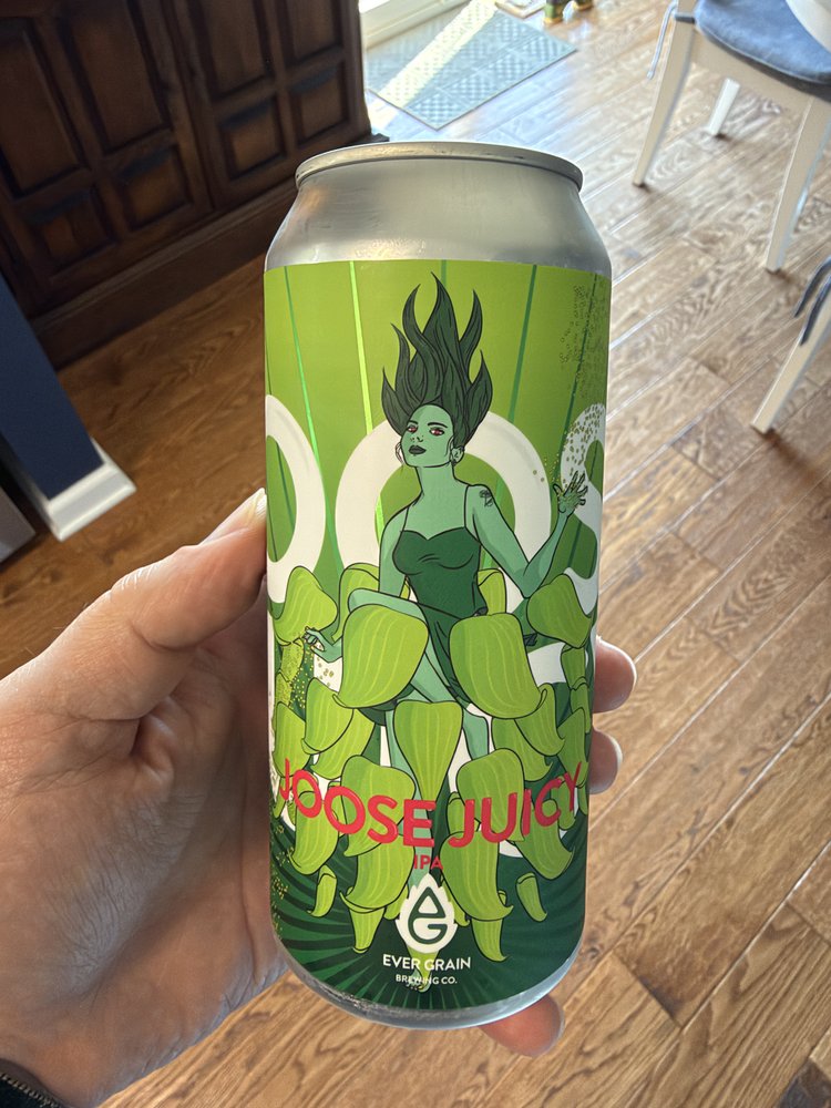 Hand holding a green beer can labeled "Goose Juice" from Ever Grain Brewing Co., featuring an illustrated woman with spiky hair surrounded by hop designs.